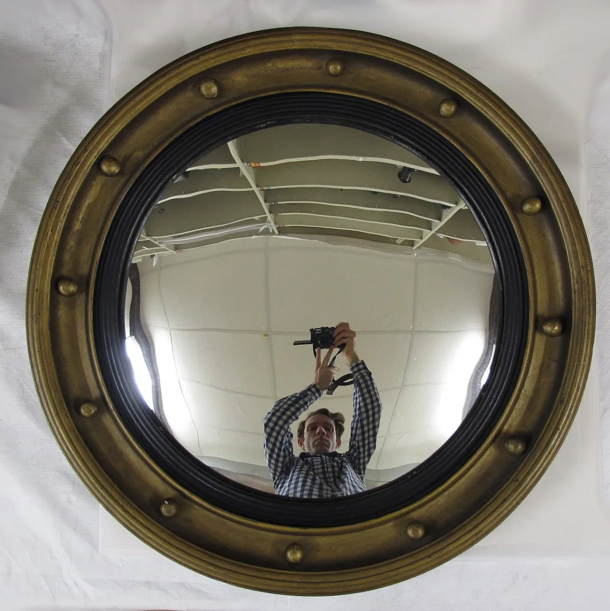 Ronde bolle wandspiegel met gouden lijst en decoratieve knoppen